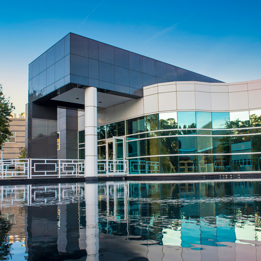 Exterior view of the Center for Marine Science - a largely glass building with a reflecting pool out front.