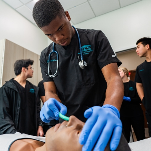 Respiratory therapy student practices using an nasopharyngeal airway on a manakin