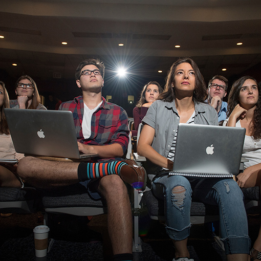 Students in a theater taking notes on laptops