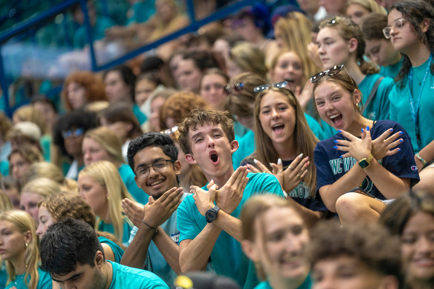 Group of students making 'Wings Up' salute with their hands.