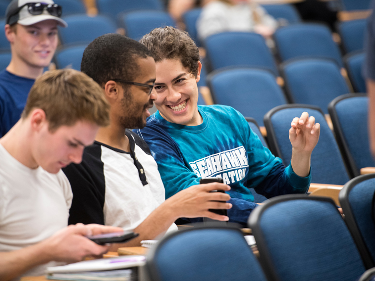 Students laughing in class. One is pictured wearing a Seahawk Recreation shirt.