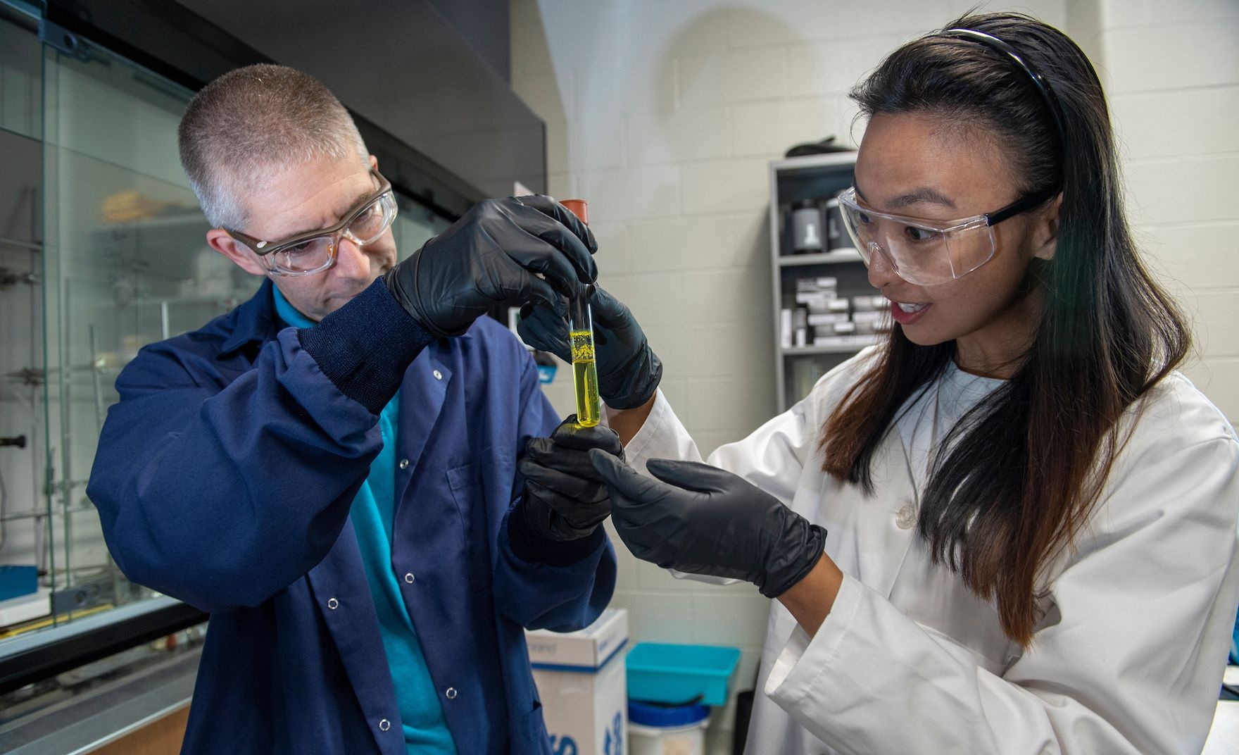 Two people inspecting vial in a lab