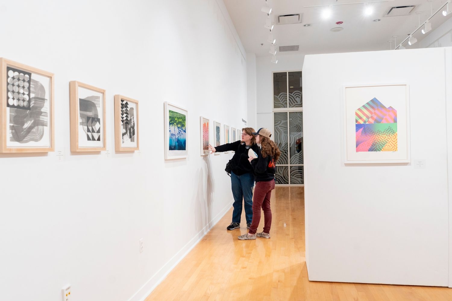 Two people examine the art in the CAB Gallery