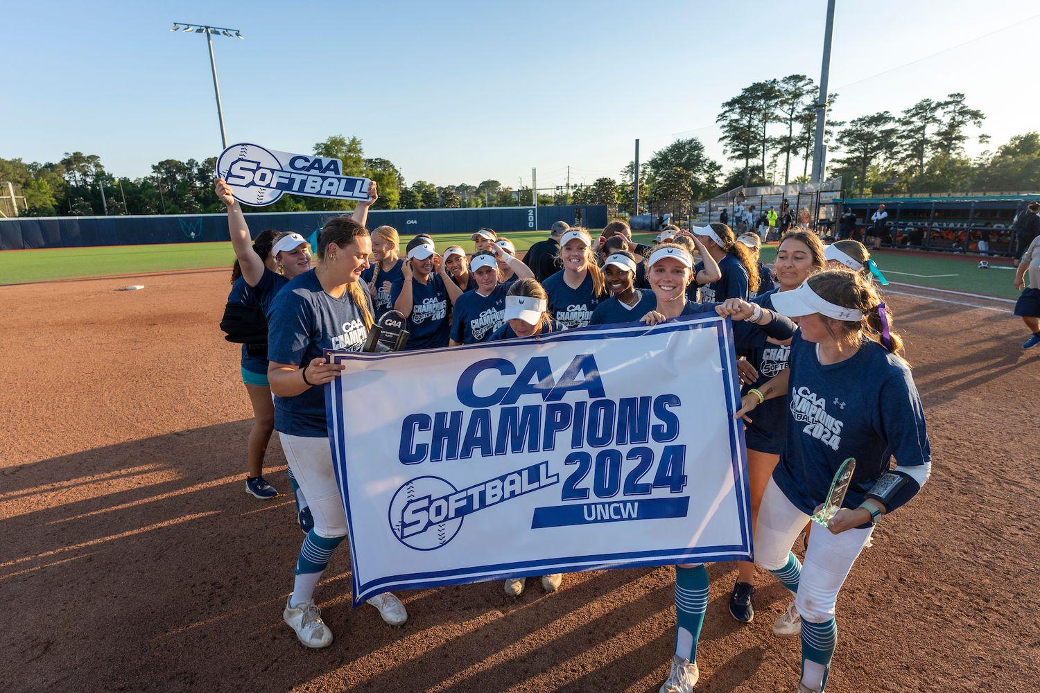 UNCW's CAA-Championship-winning team poses with banner about their win