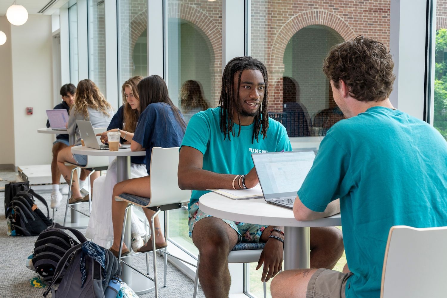 Two students sit at a table outside Discovery Hall