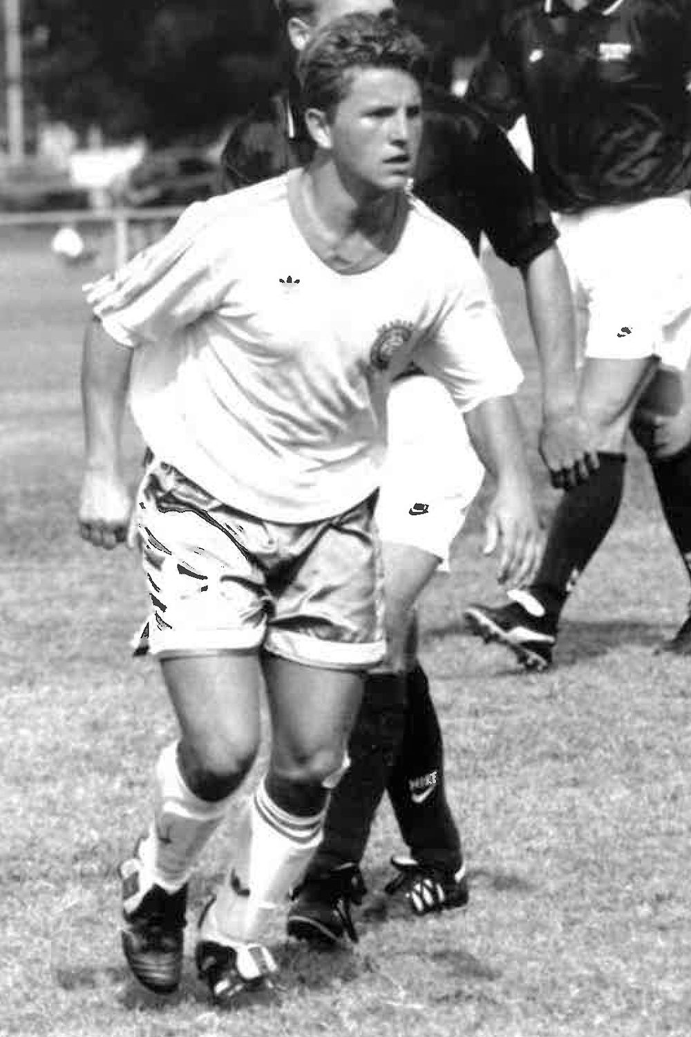 A black and white photo of Dr. Steve Elliott in a UNCW soccer uniform, playing soccer.