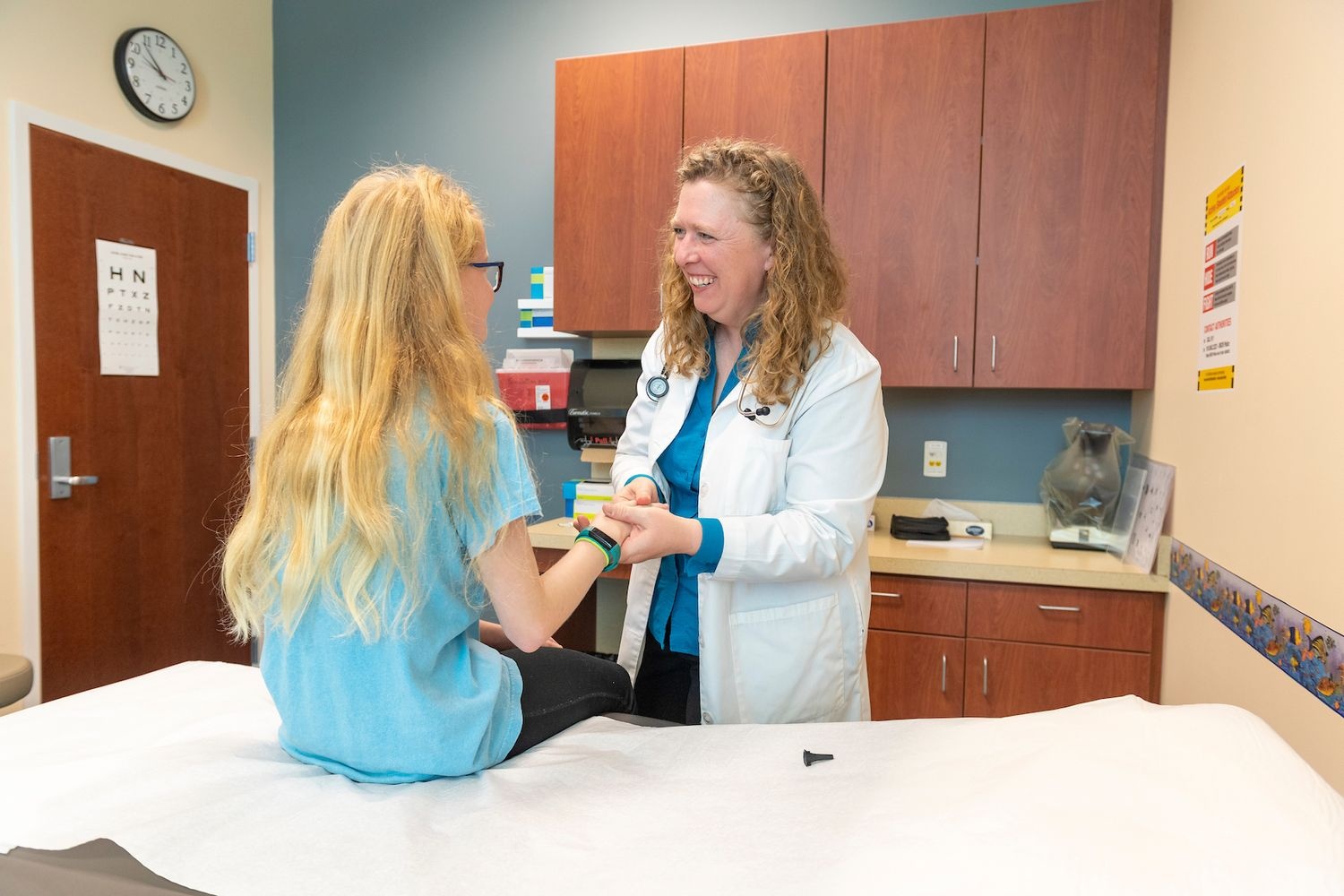 A doctor smiles at a young patient while examining her