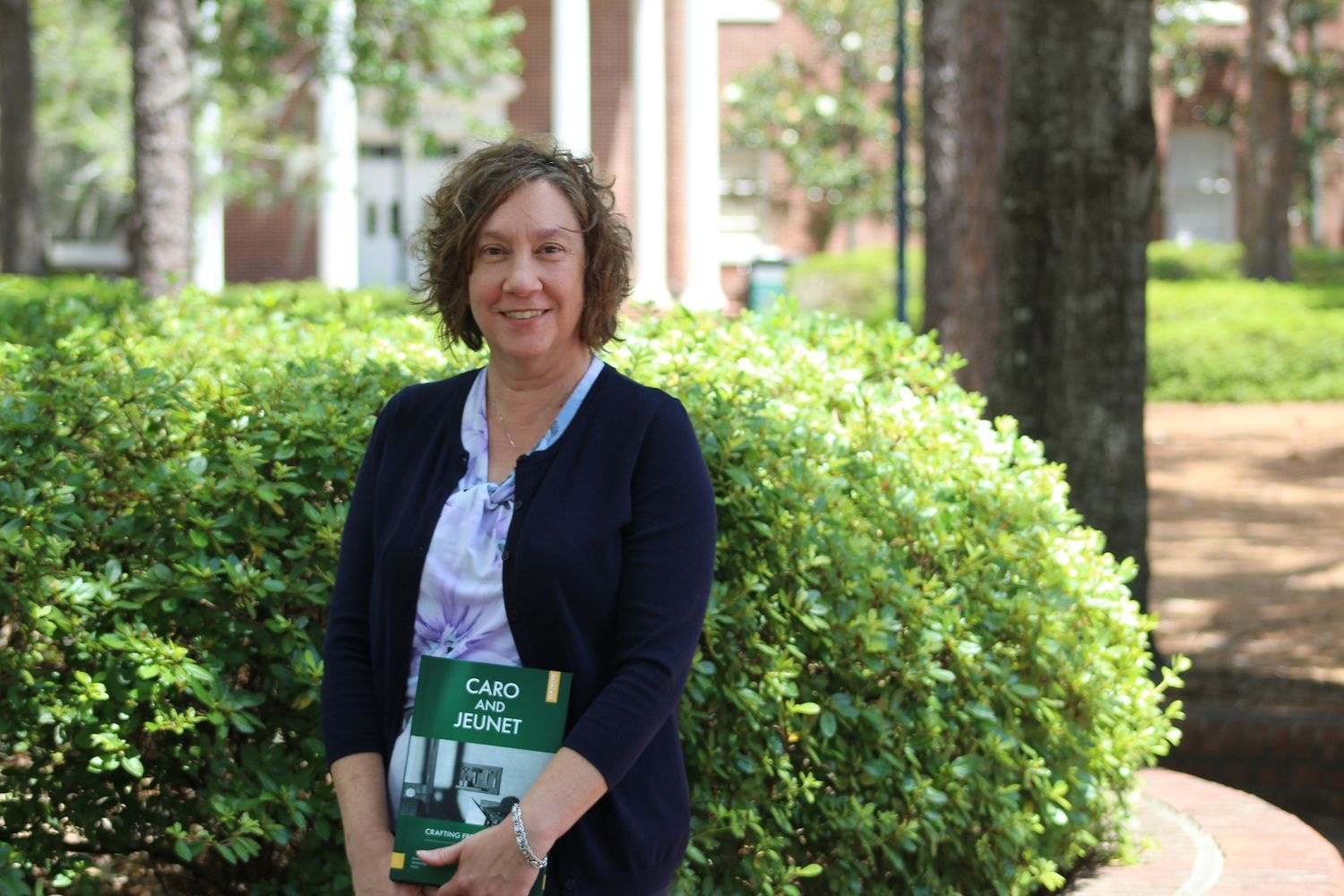 Michelle Scatton-Tessier stands outside Bear Hall with a copy of her new book