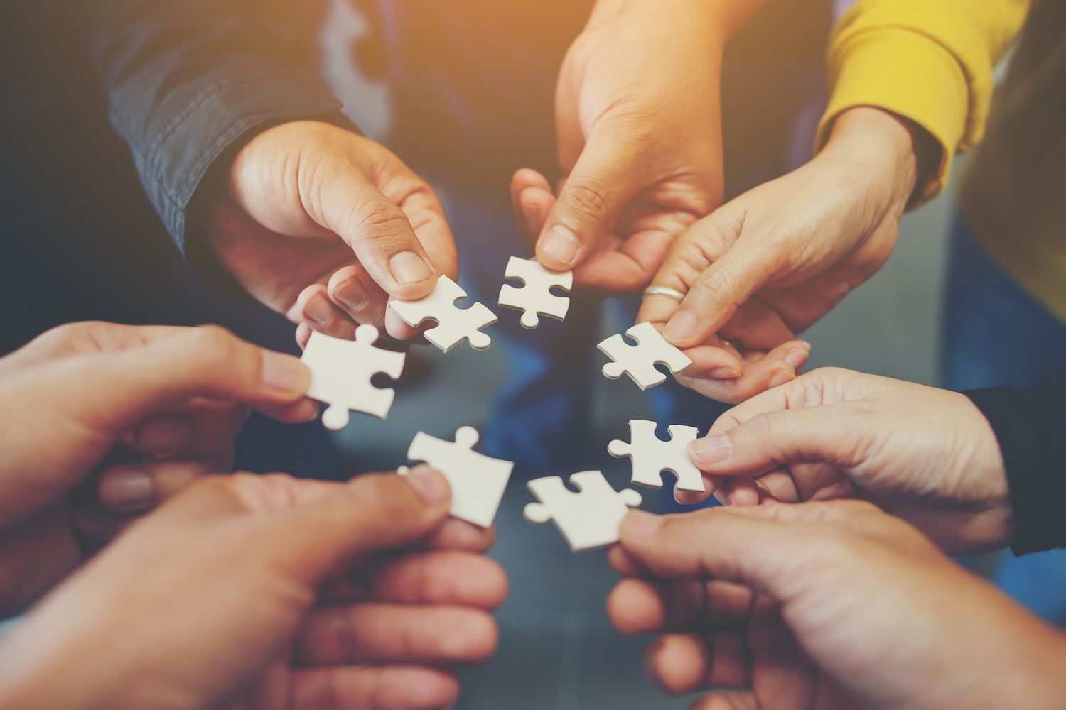 circle of hands with puzzle pieces