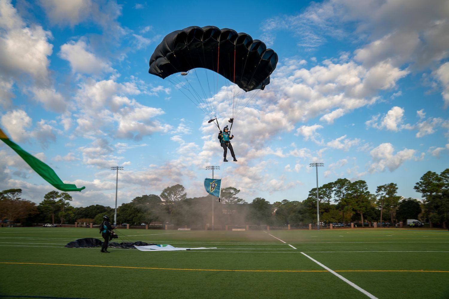 Parachutist with UNCW flag lands on grass