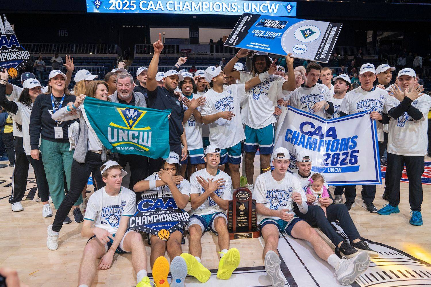 Men's basketball team celebrates CAA Championship displaying banners, signs and trophy
