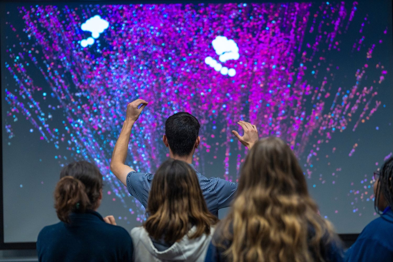 People look at a large screen projection during a computing showcase.