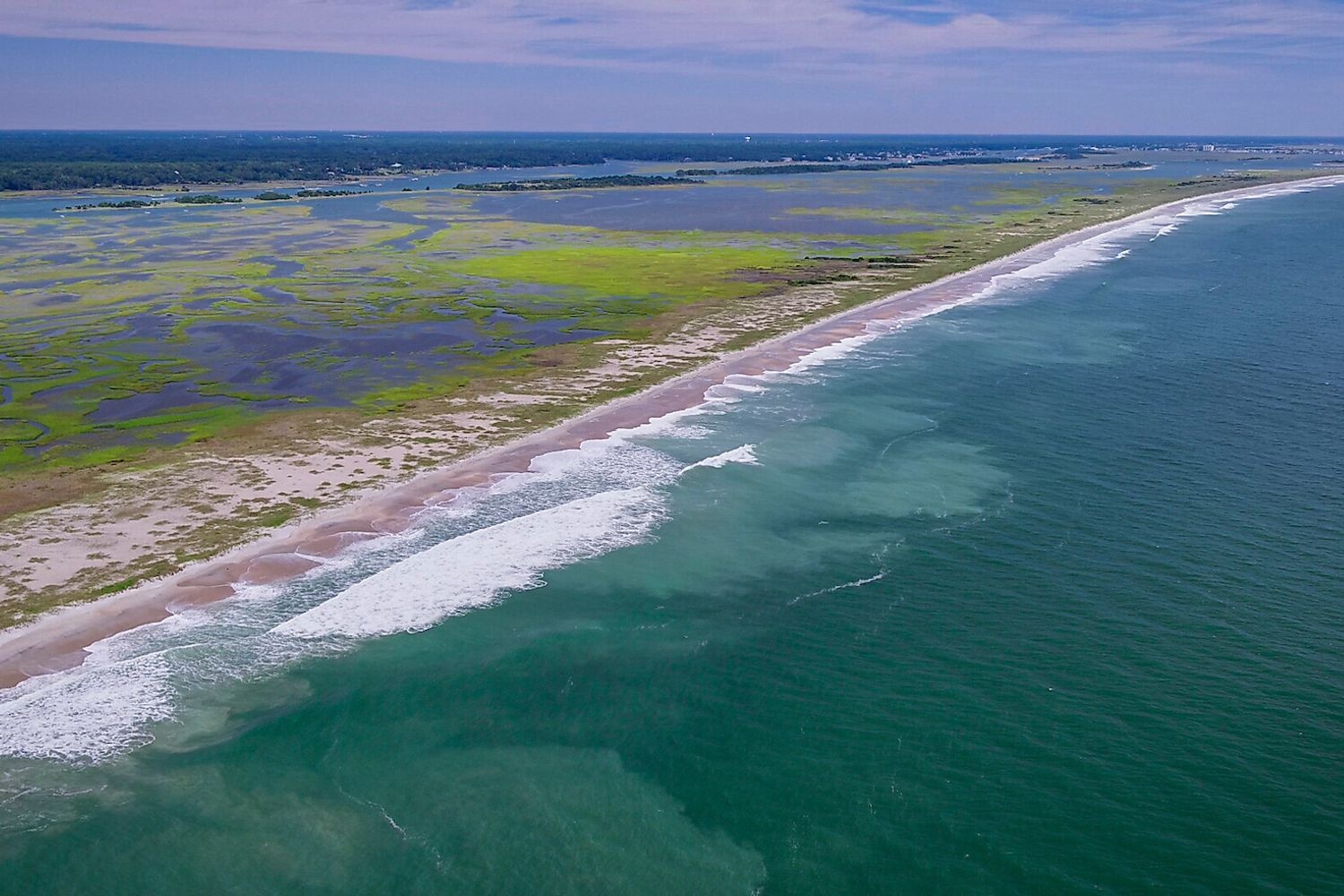 a birds eye view of masonboro island on the left and bright blue water to the right