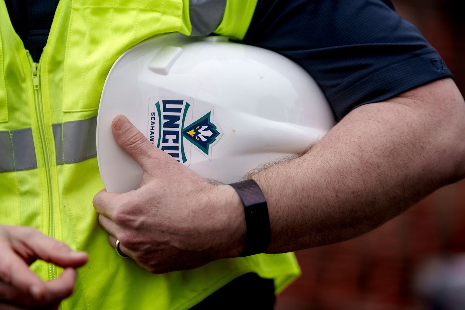 Construction worker holding hard hat with UNCW Seahawk logo