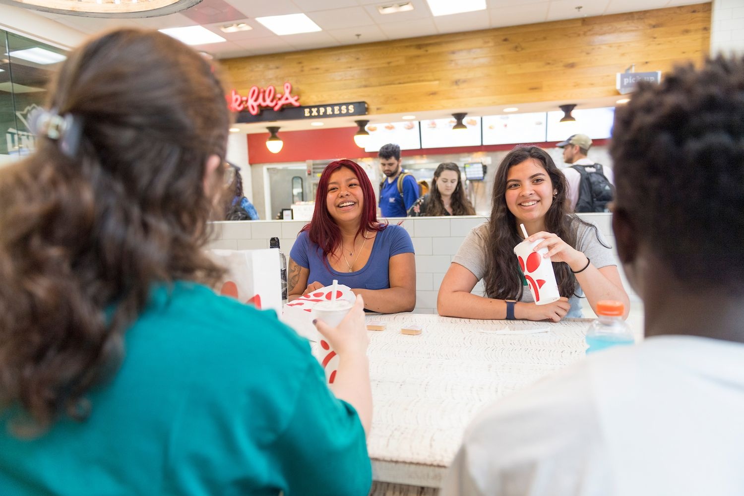 Students sitting at a table with drinks and food from Chick-fil-A