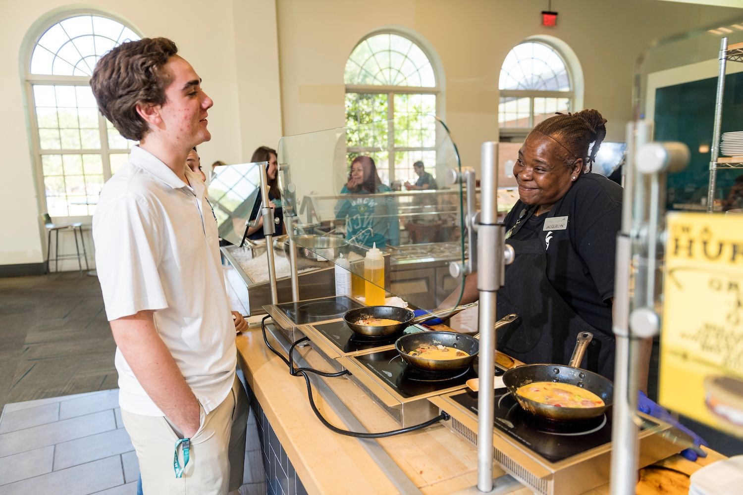 A student in front of an omelet station talking to the server