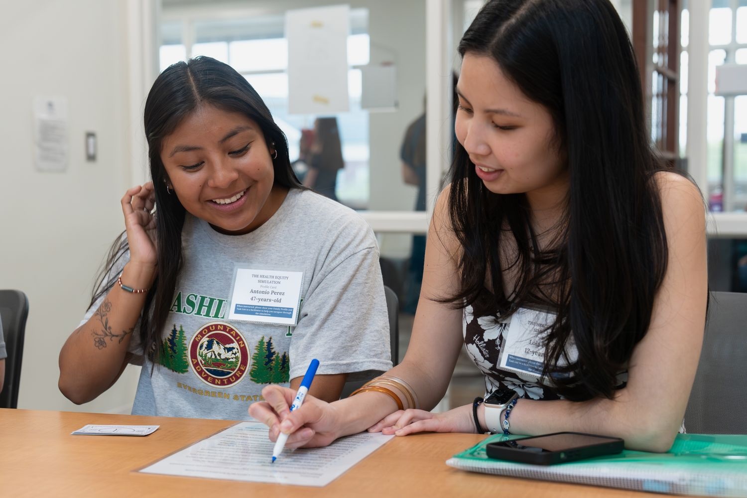 Two students take a test as part of the Health Equity Simulation which is designed to engage students in collaborative, community‑based learning focused on social determinants of health in southeastern North Carolina. 
