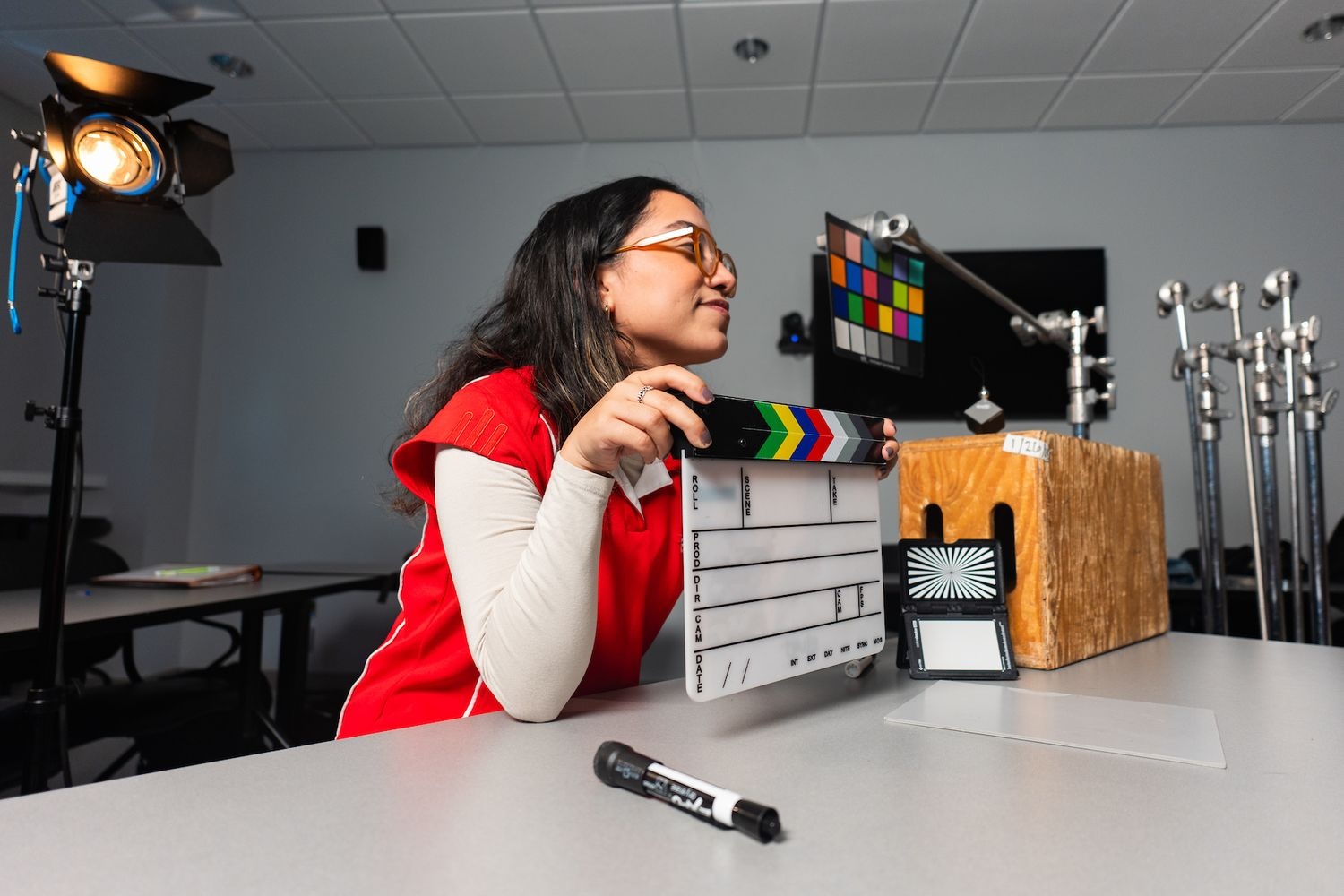 Student holding a clapper board leaning on a desk