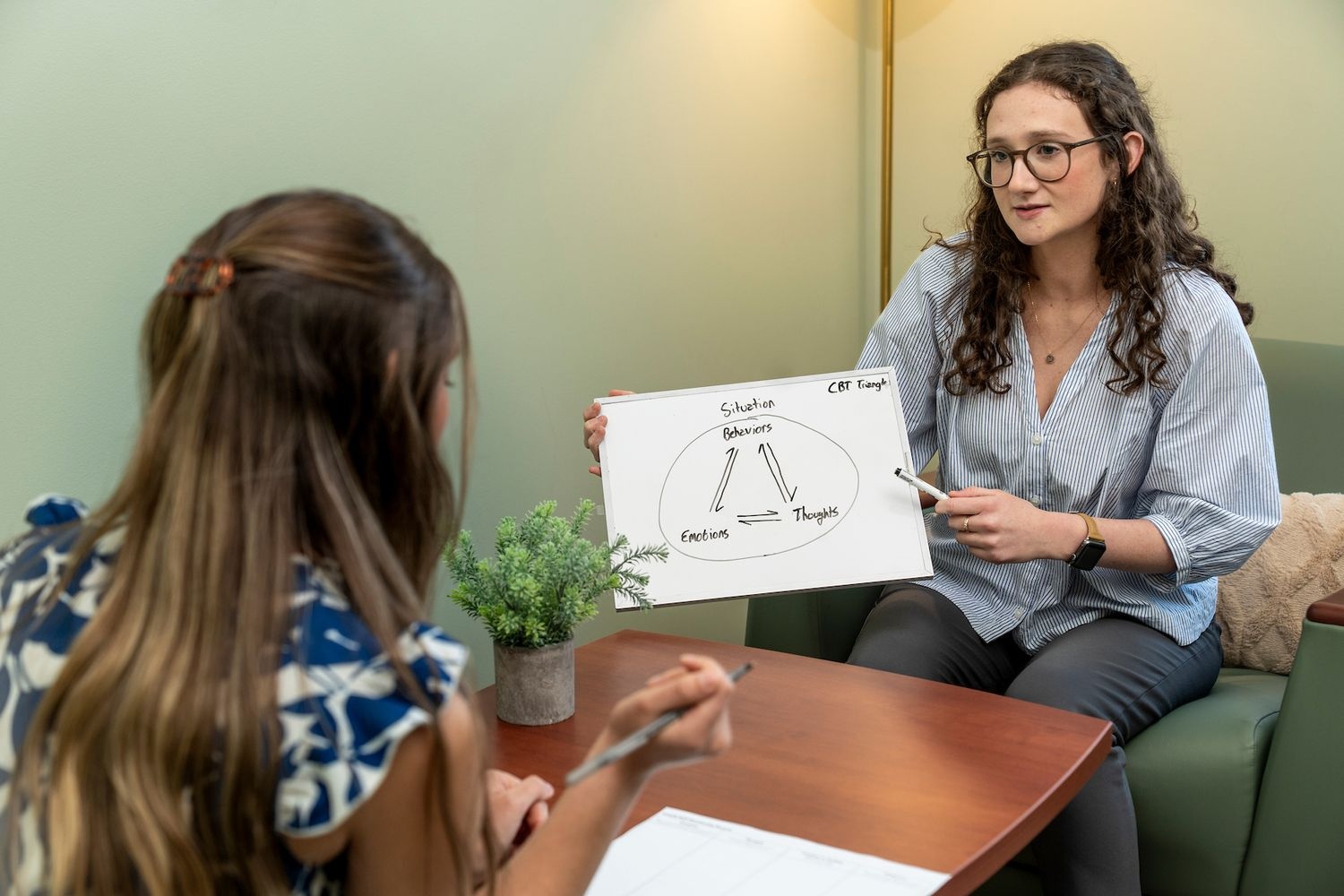 GPAC member holding up a CBT triangle on a whiteboard while speaking with someone