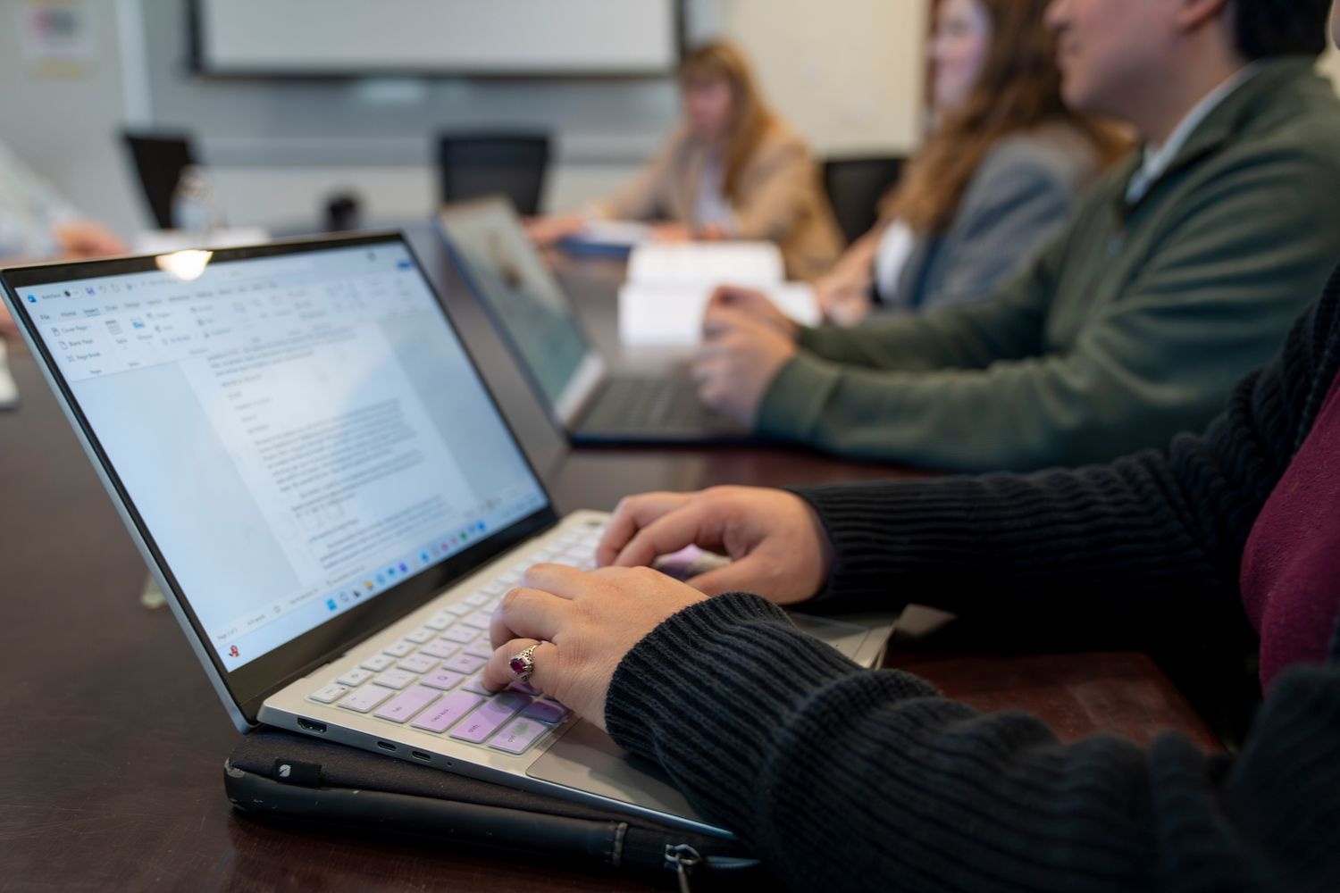 People typing on laptops sitting at a GPAC meeting table