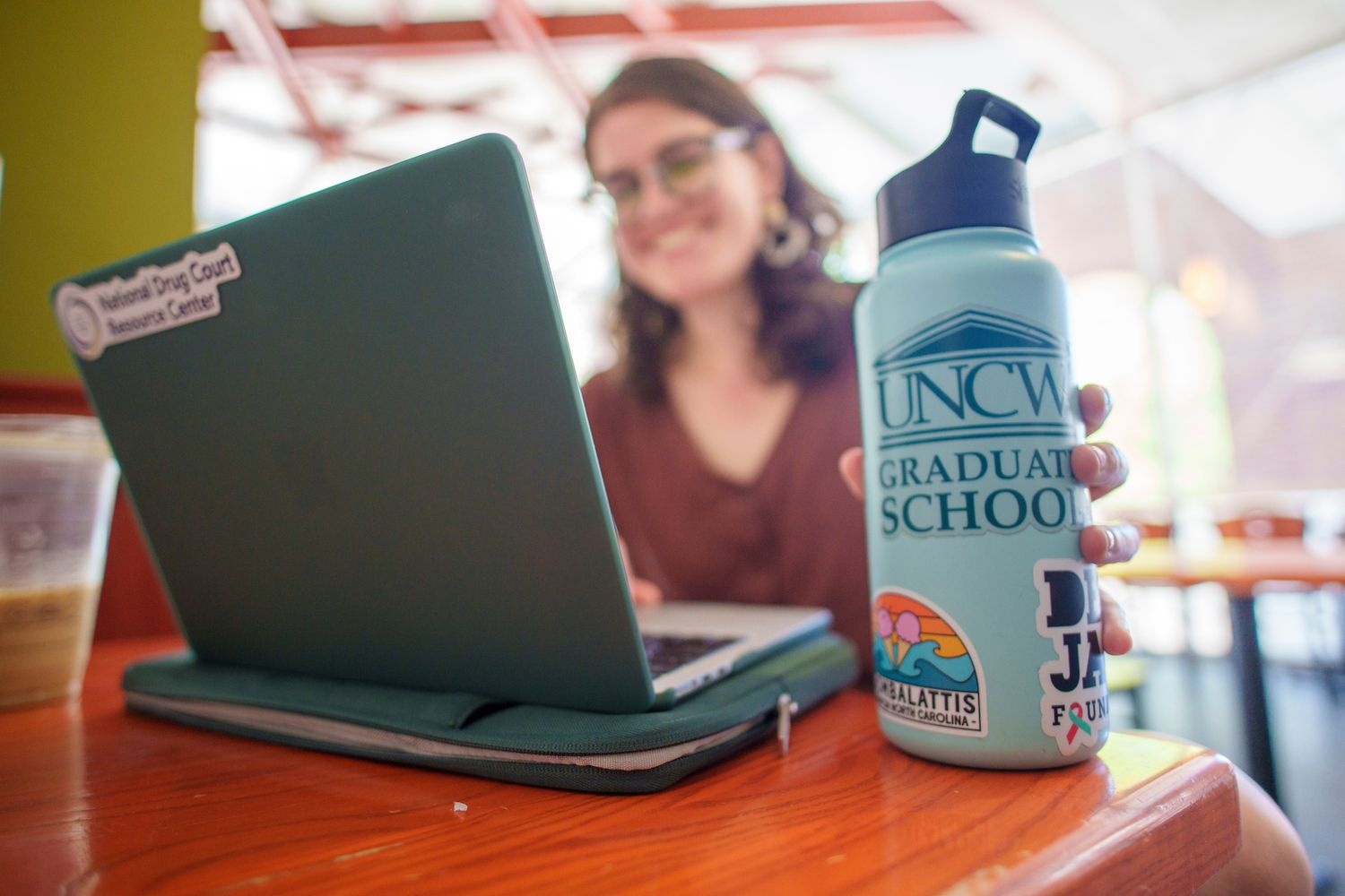 student in front of laptop with graduate school water bottle