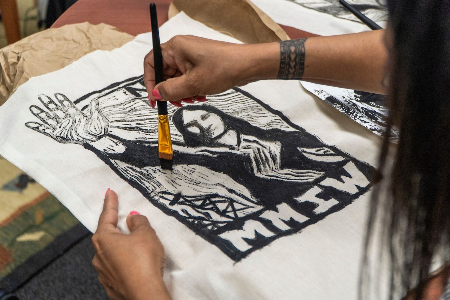 Person painting a MMIW design on fabric