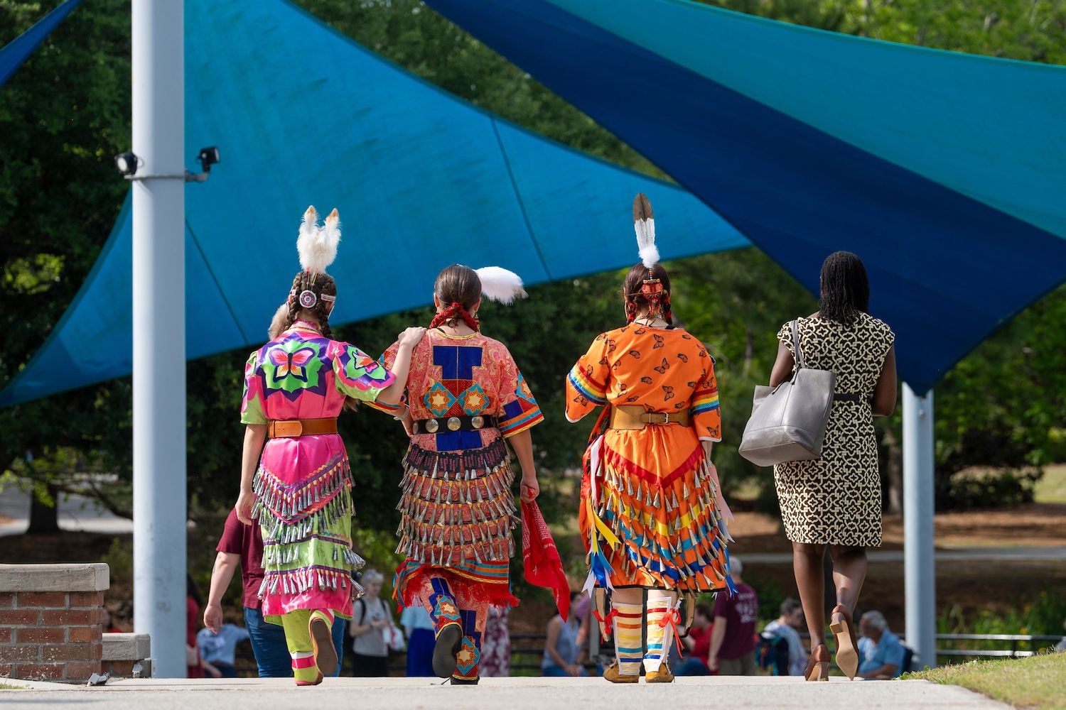 The backs of women walking in Indigenous garb