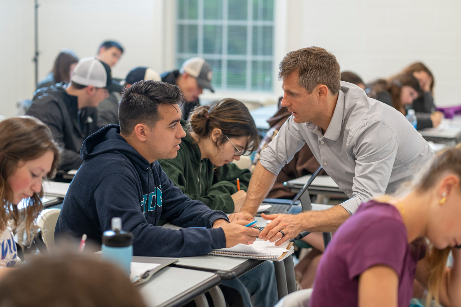 faculty member helps students in class