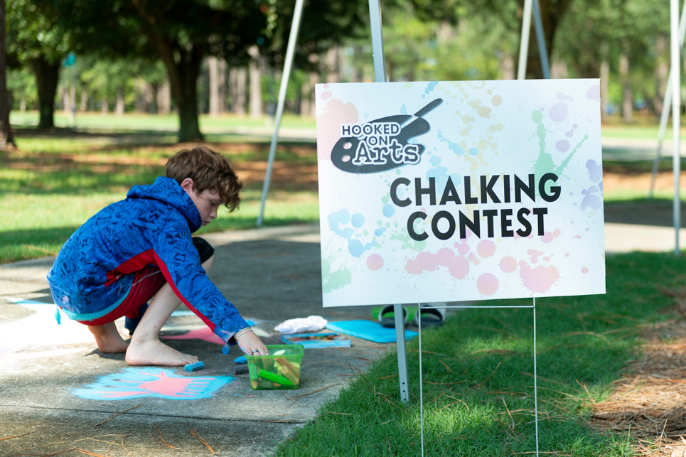 Child draws on sidewalk with chalk for a contest.