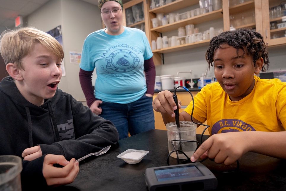 two kids and teacher perform science experiment with shocked faces