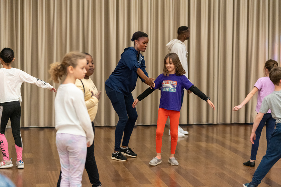 Student instructs youth during dance class