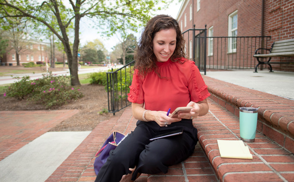 Student seated on lawn in front of Hoggard Hall studies