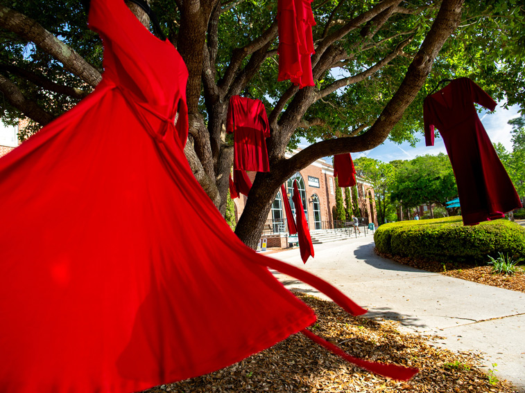 Red dresses hanging from tree