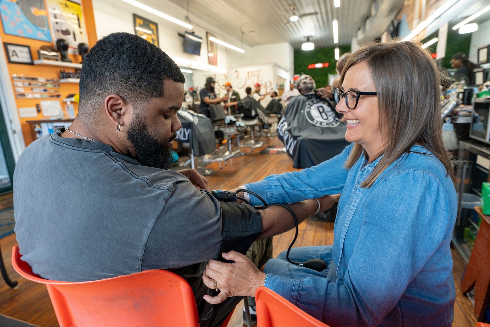 UNCW School of Nursing faculty member Stephanie Turrise checks the blood pressure of Justin Dillard '22 a regular at Just Cut It Barbershop on Castle Street in Wilmington.