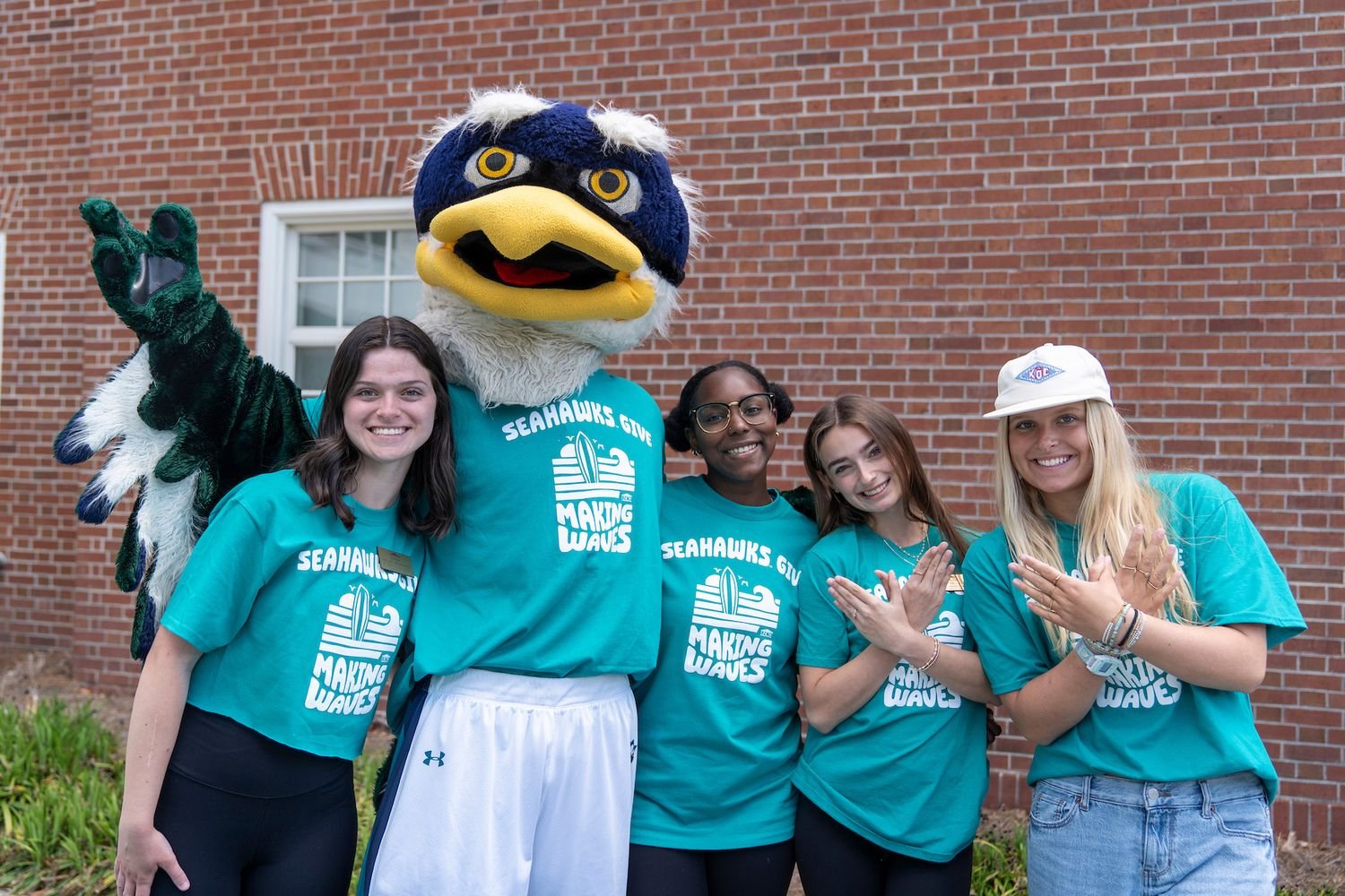 Sammy C. Hawk poses with students at the kickoff event for Seahawks Give.