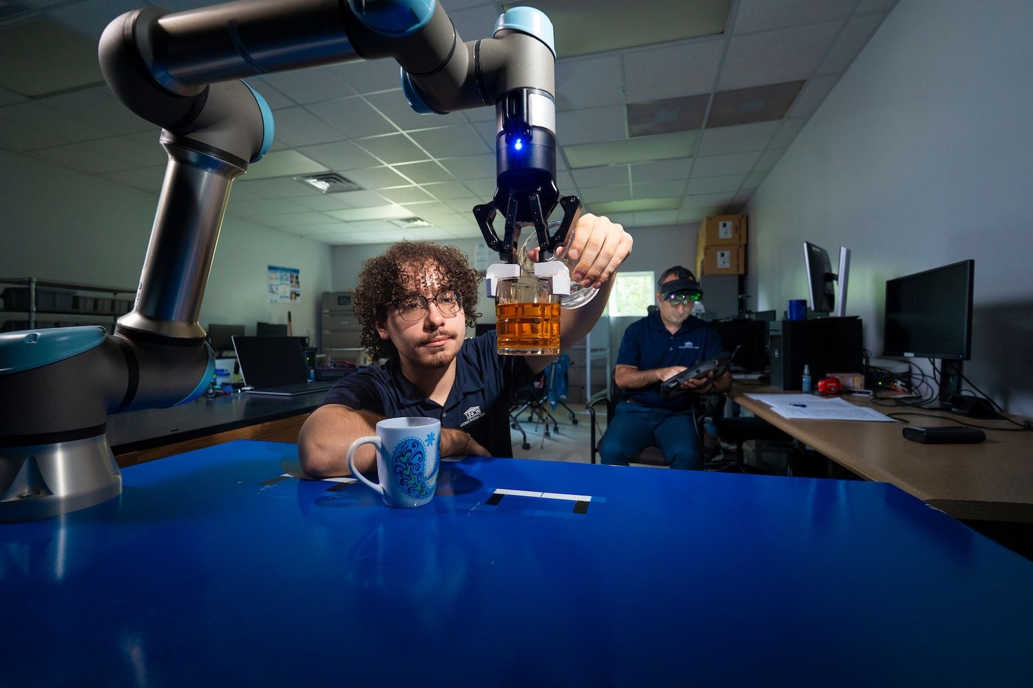 UNCW student researcher prepares robotic arm for a test