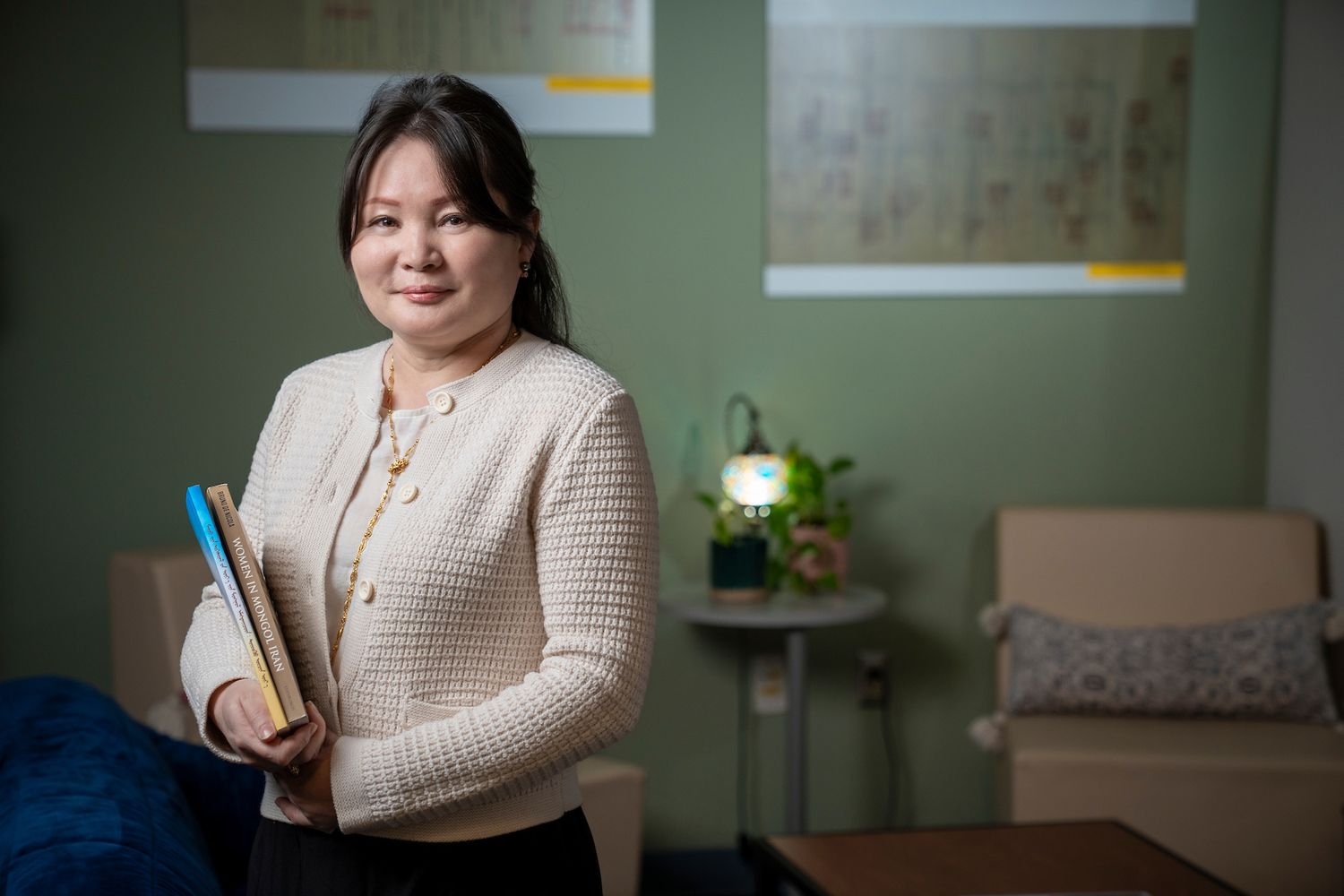 Woman in an office holding a book. 