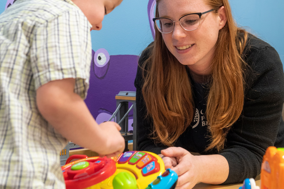 A student works with a child holding a kid’s toy