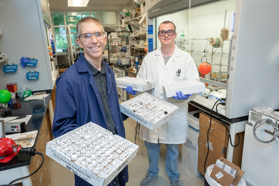 Professor and student holding boxes of lab equipment