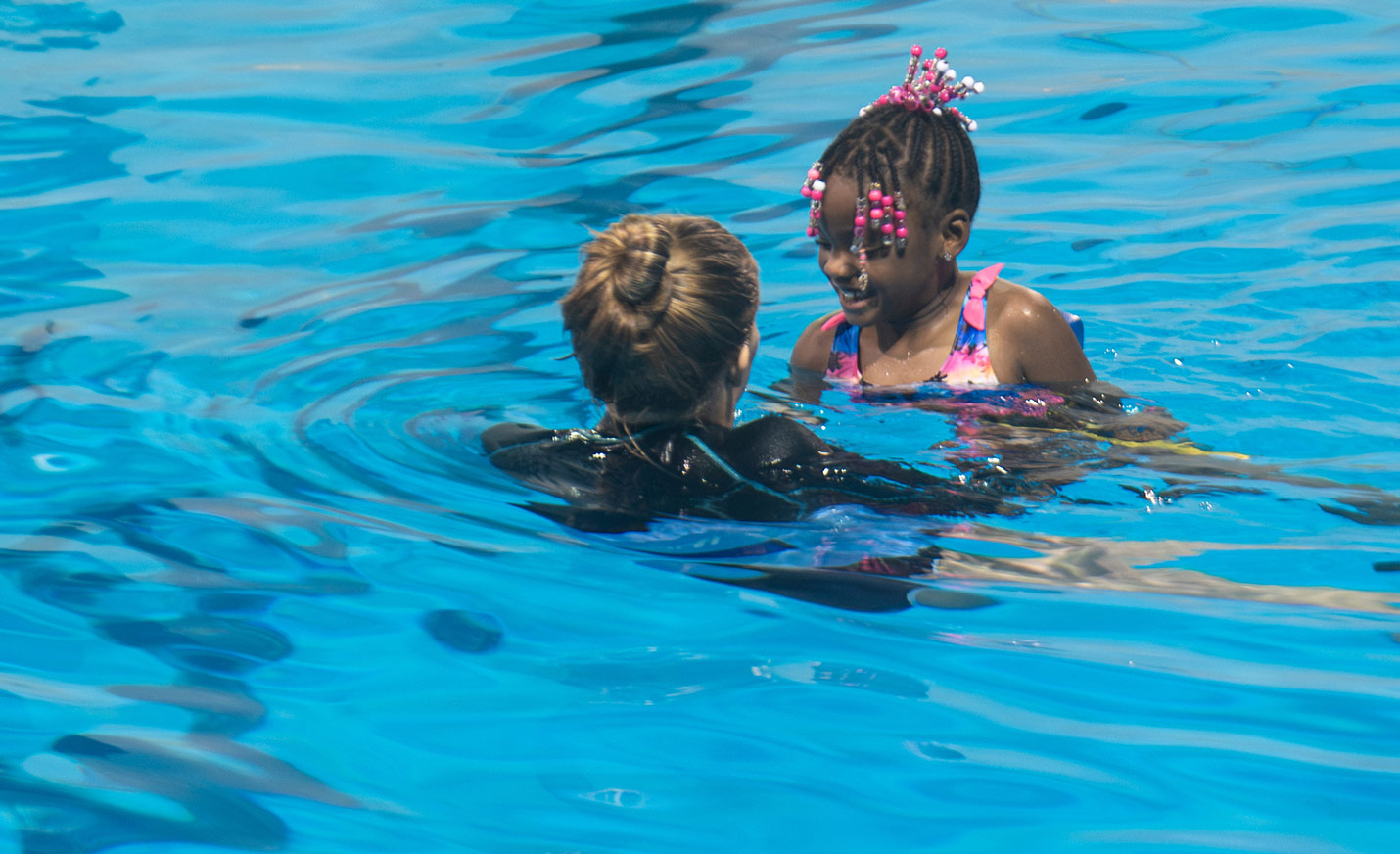 Instructor provides lessons to student as they both hold a kickboard