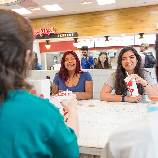 Students sitting at a table with drinks and food from Chick-fil-A