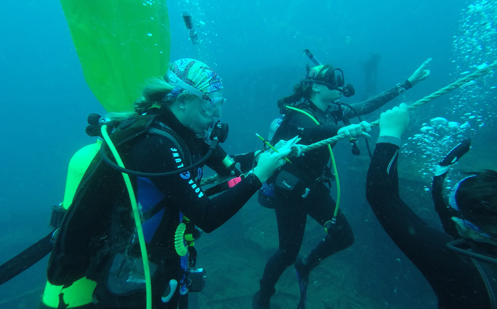 students taking notes underwater during scuba diving session