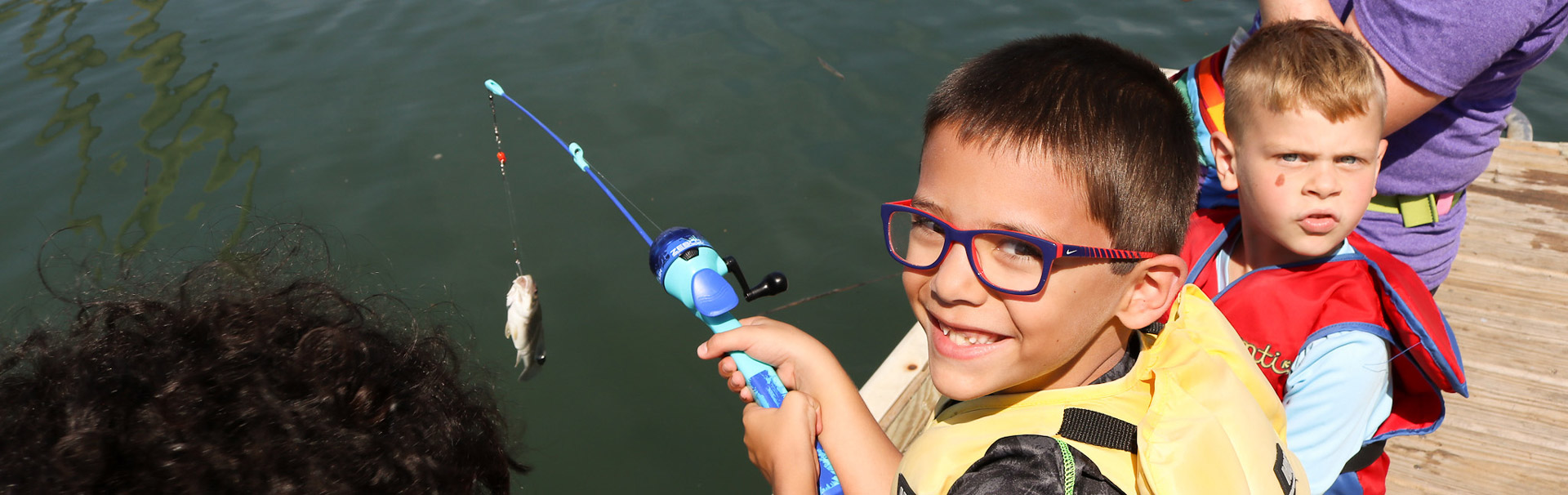 Kid holding a fishing rod with a fish on the line