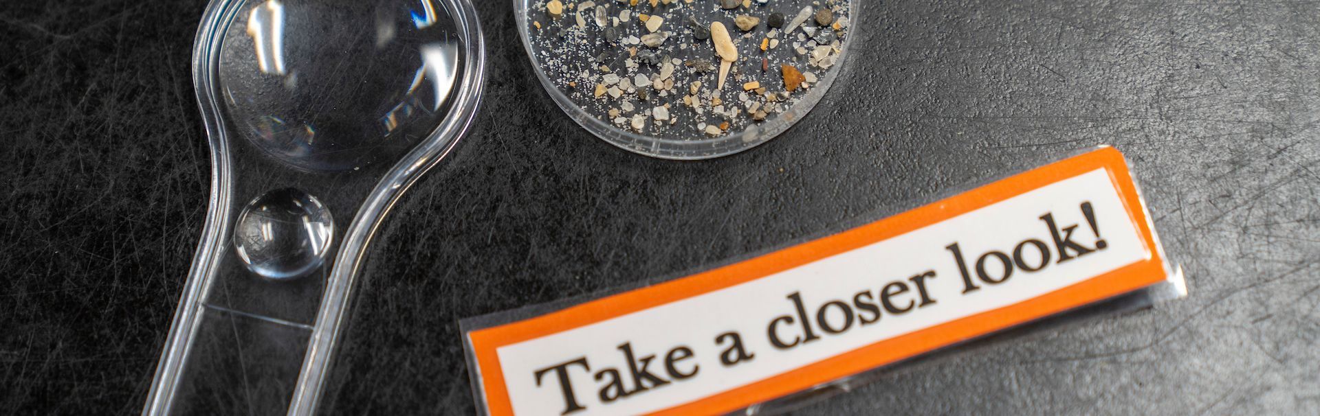Magnifying glass and petri dish with text saying, "take a closer look!"
