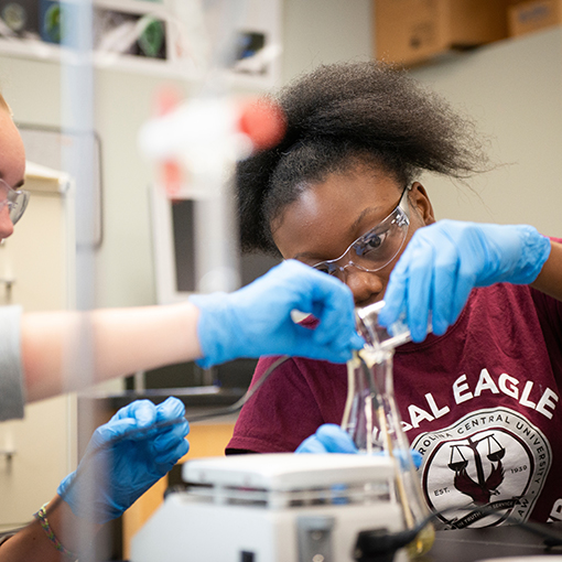 Two girls pour liquid into a vial in one of UNCW’s marine labs