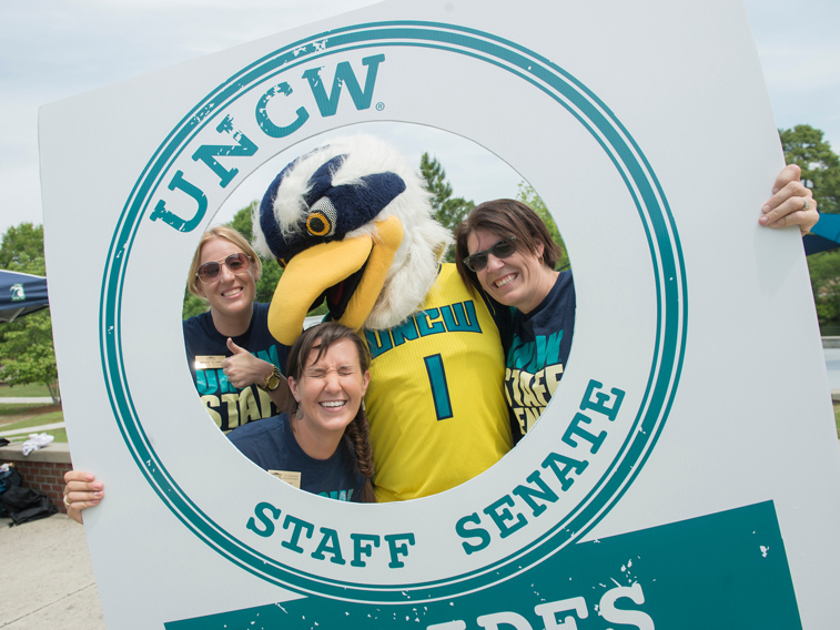 People and Seahawk mascot holding up a staff senate sign