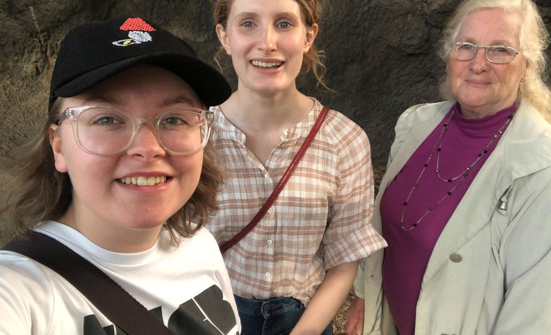 3 women smiling in front of a rock wall